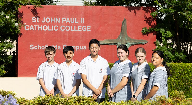 Junior students posing in front of St John Paul II Catholic College Schofields