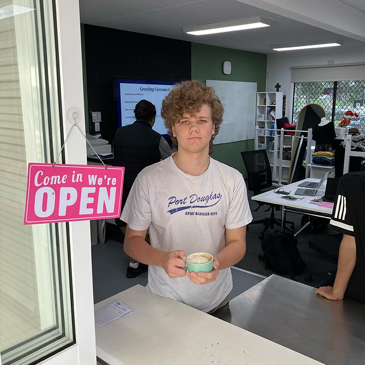 CSPD student roleplaying as a cafe worker. They are serving a cup of coffee