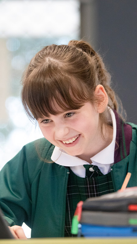 Holy Cross Glenwood student in class. The student is typing on her Chromebook.