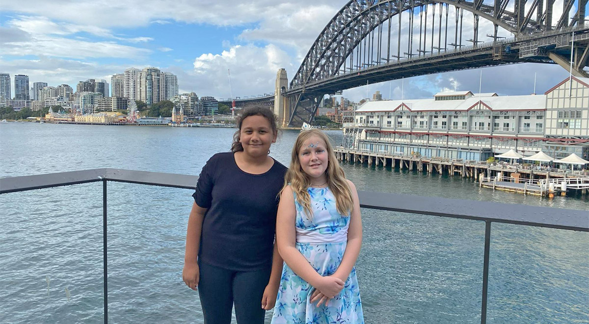 St Patrick’s Primary Parramatta students Eimear Mitchell and Sonia Sitoa standing in front of the Sydney Harbour Bridge