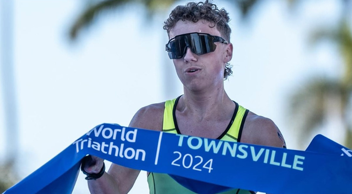 Para triathlete Matt Engesser running holding "World Traithlon Townsville 2024" banner